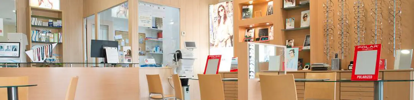 Interior de la óptica, con las estanterías de monturas y el mostrador al fondo